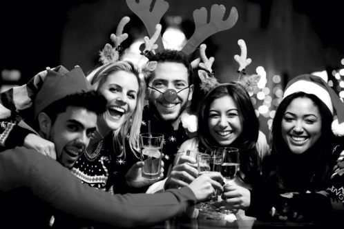 Group of friends wearing christmas jumpers smiling into camera