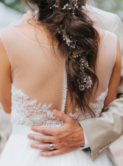 A groom places his hand gently on the back of his bride