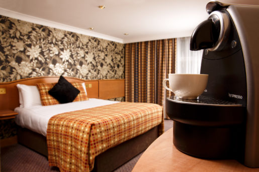 Nespresso coffee machine, with double bed in background in privilege bedroom